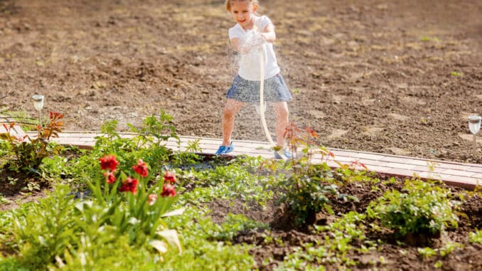 Mädchen gießt Blumen mit Brunnenwasser Mädchen gießt Blumen mit Brunnenwasser