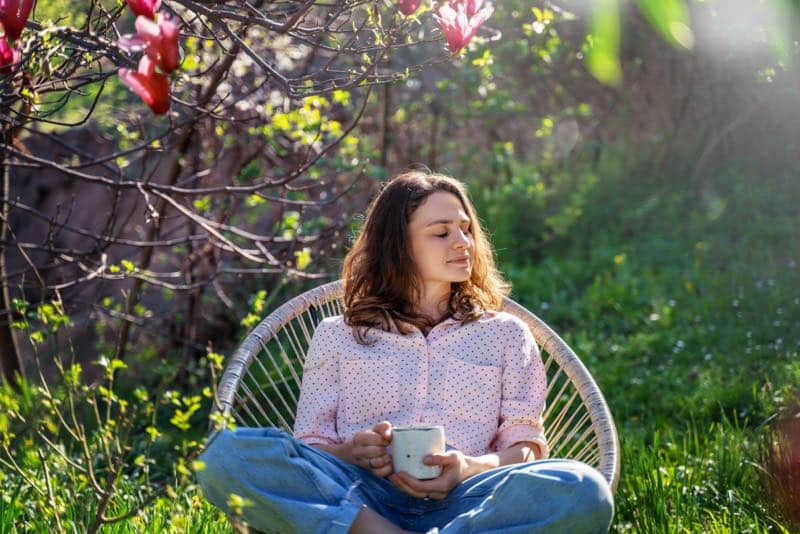 Junge Frau entspannt bei einer Tasse Tee im Garten